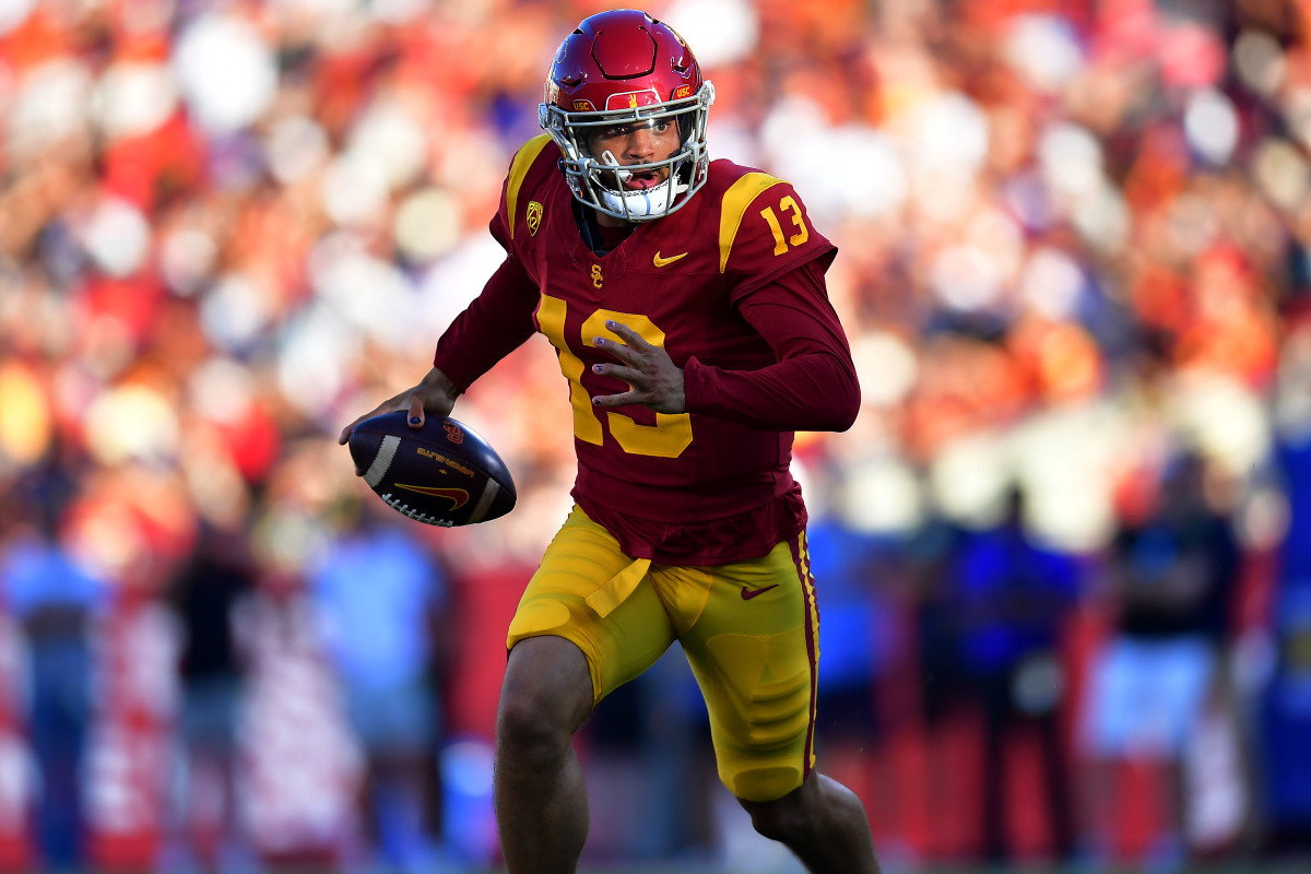Caleb Williams runs with one arm extended out by his hip holding the ball